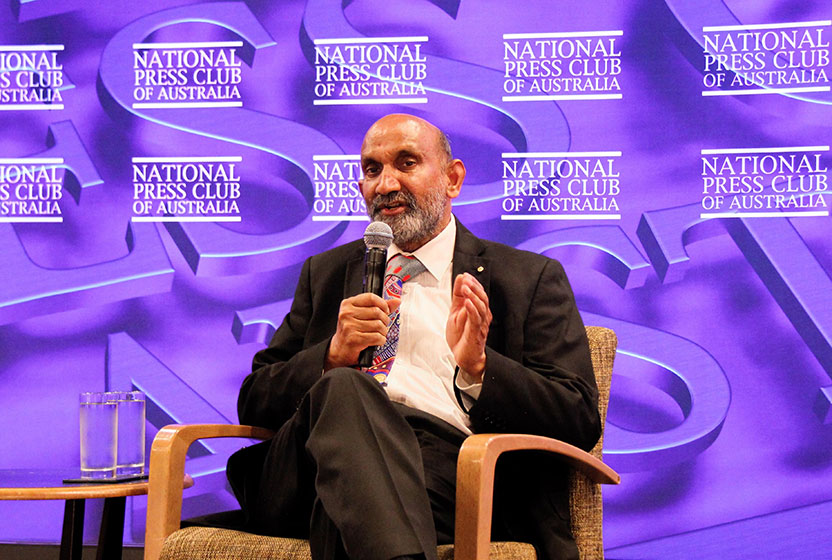 Professor Chennupati Jagadish on the National Press Club stage, sitting in a chair and speaking into a microphone
